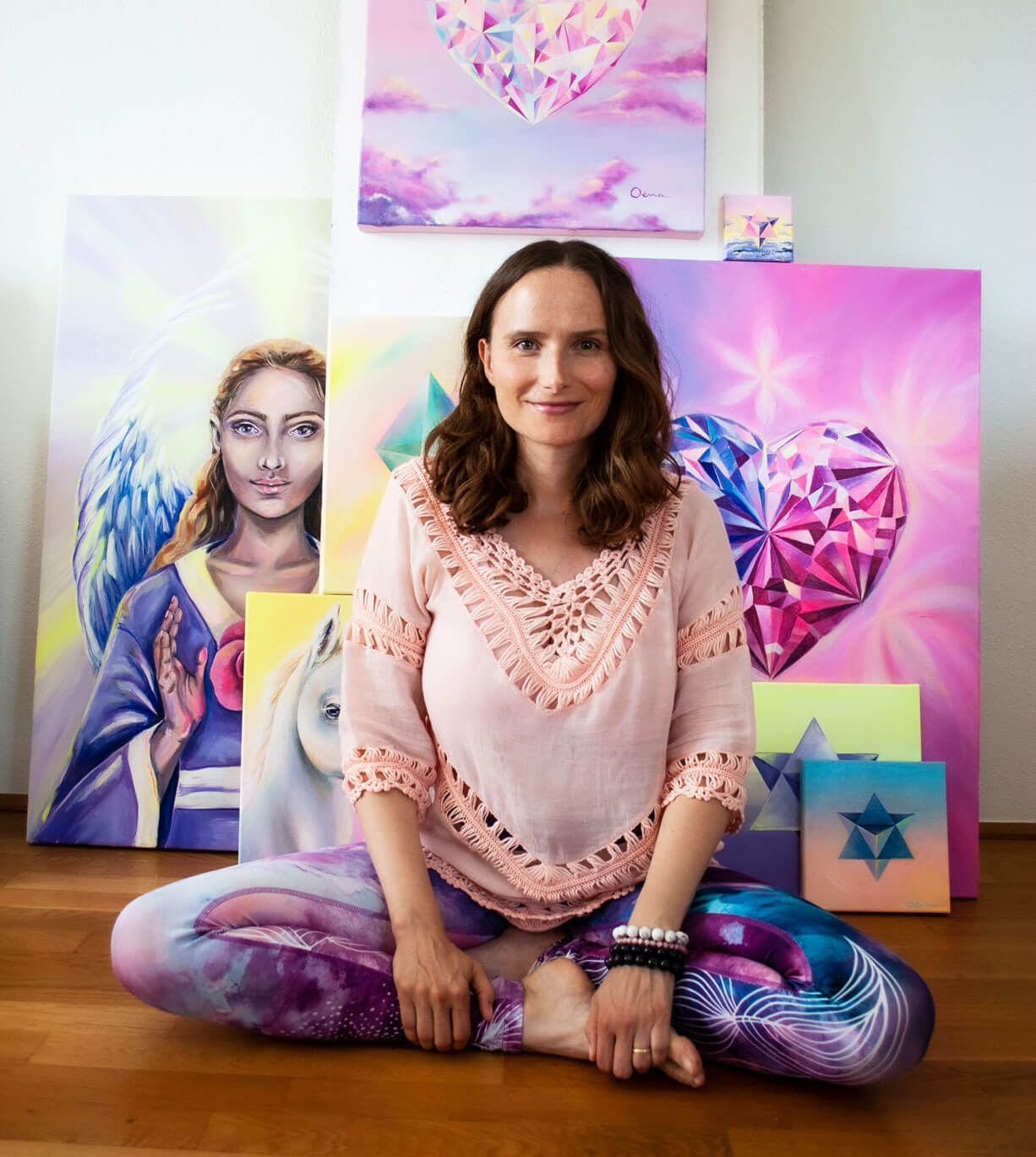 Spirituelle Künstlerin vor Kunstwerken mit Engel; Herzkristallen und heiligen Geometrien