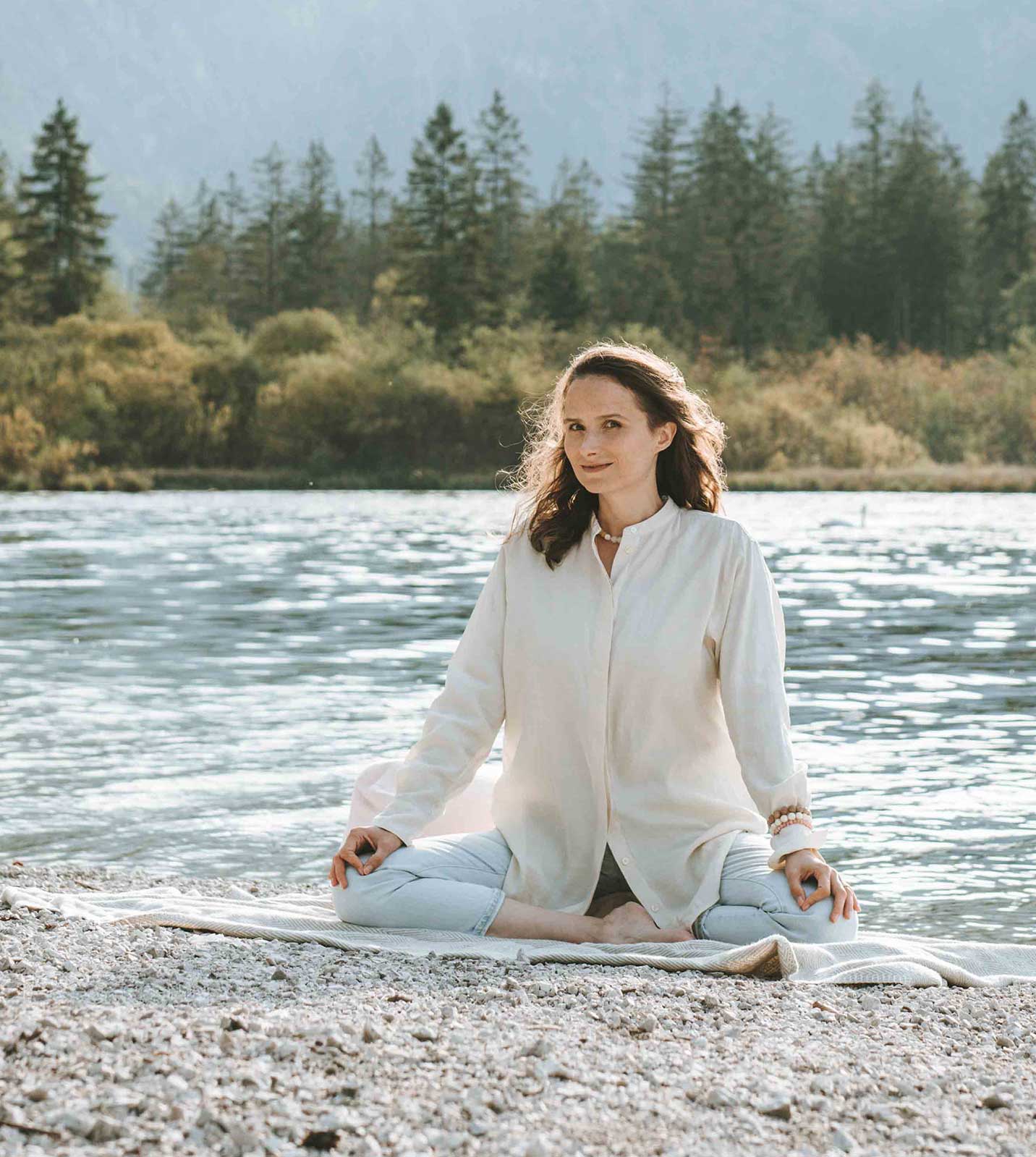 Meditationslehrerin, Meditationscoach in Meditationspose vor See mit Wals- und Bergpanoram